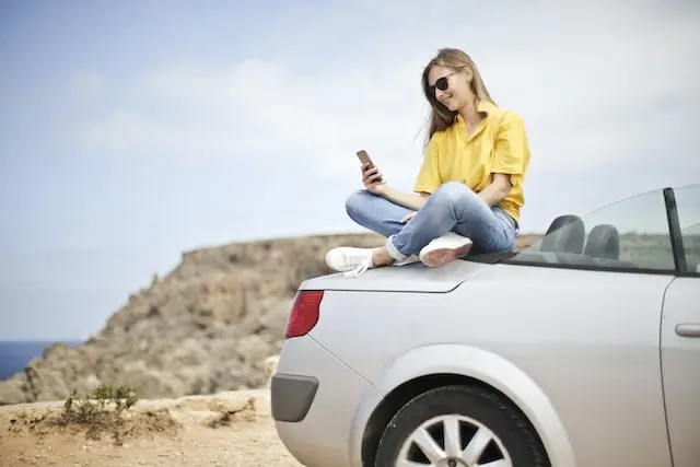 A-woman-sitting-in-a-car-and-looking-at-a-smartphone