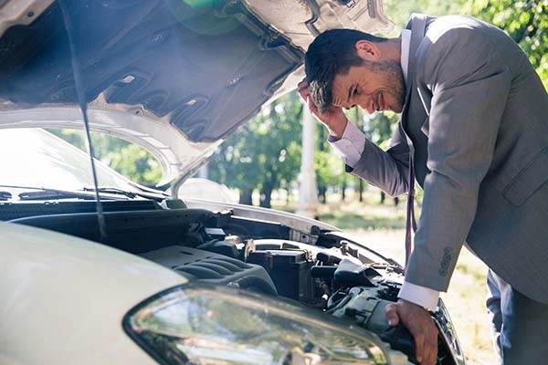 A man in a suit checking his car engine