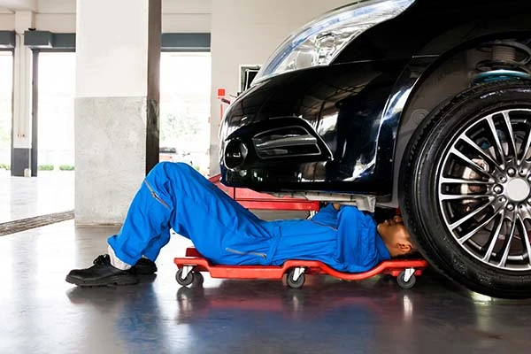 A mechanic fixing a car from underneath