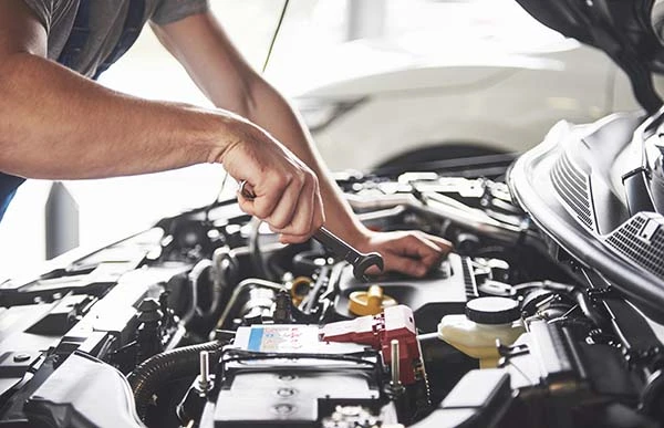 A man using a wrench to fix his parking brake cable