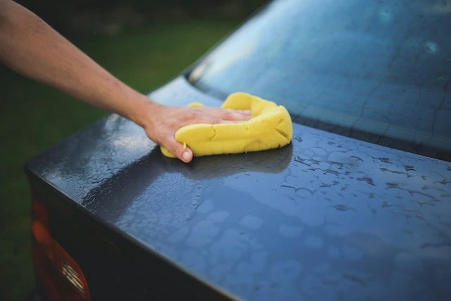 A person off-screen cleaning their car with a cloth