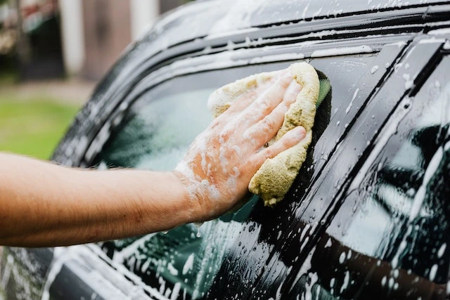 A person off-screen wiping a car window with a rag