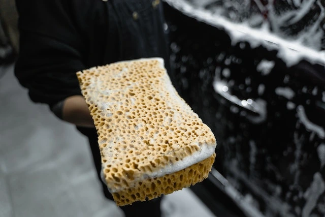 An unknown person holding a soaped-up sponge