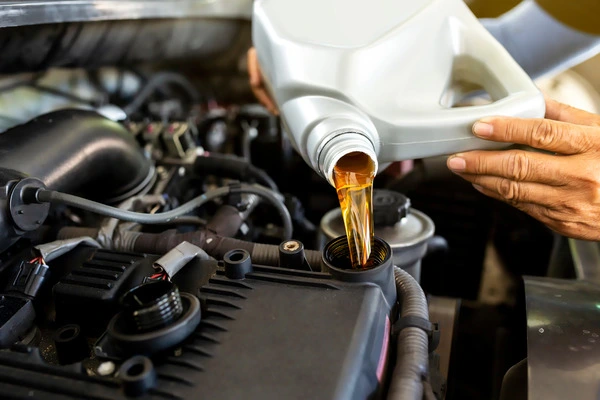 Car-mechanic-replacing-and-pouring-fresh-oil-into-engine