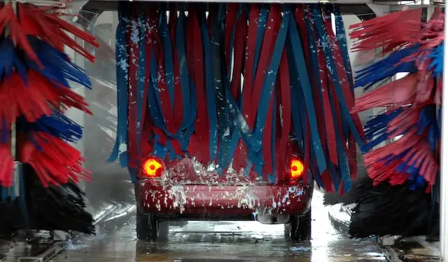 A-red-car-going-through-blue-and-red-brushes-at-a-car-wash