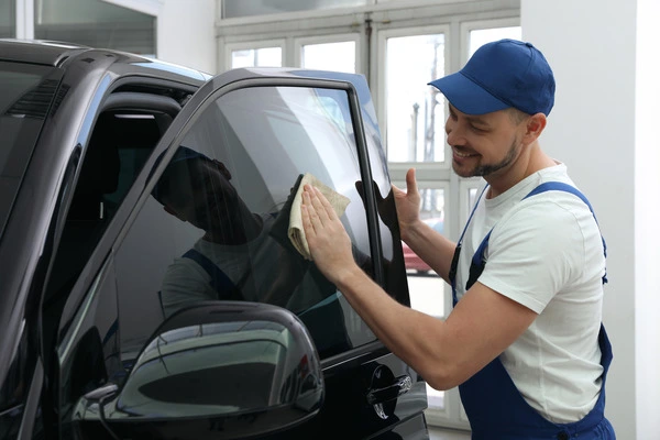 Mechanic-wiping-down-a-tinted-car-window