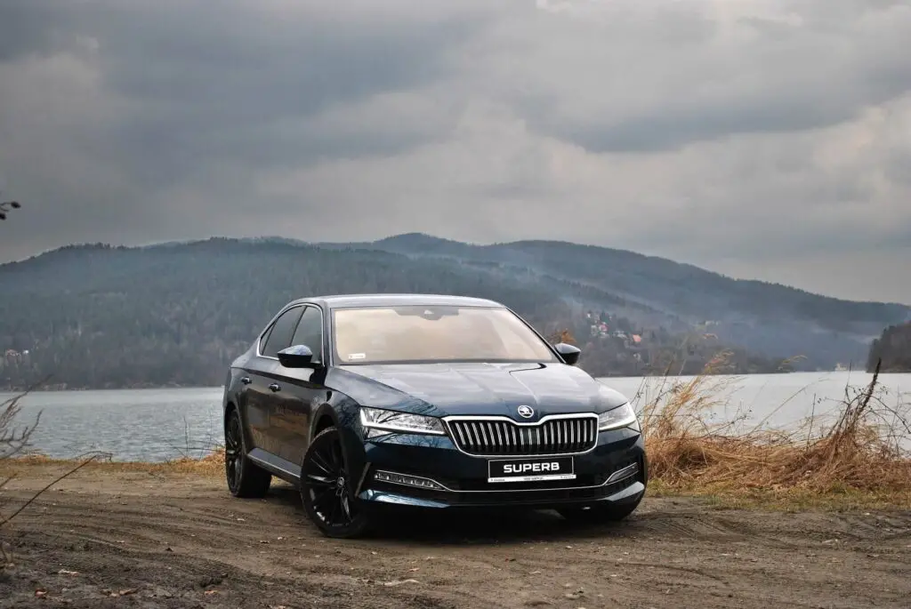 A black Skoda Superb car parked on a dirt road