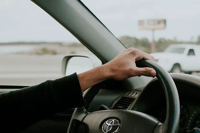  A person holding a Toyota steering wheel