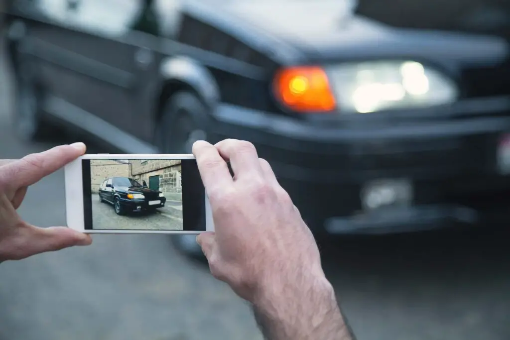 Man taking photo of a car on his phone.