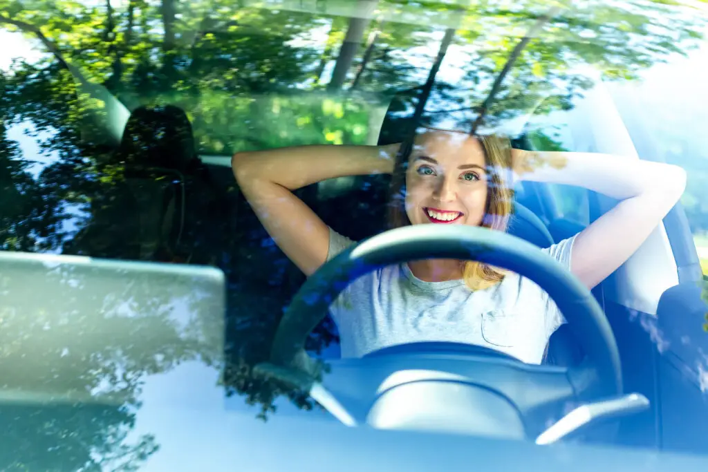 A woman sitting behind the wheel smiling
