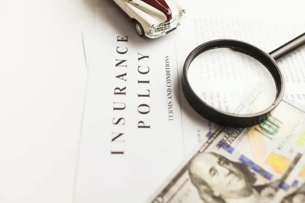 Car insurance papers with money and a magnifying glass