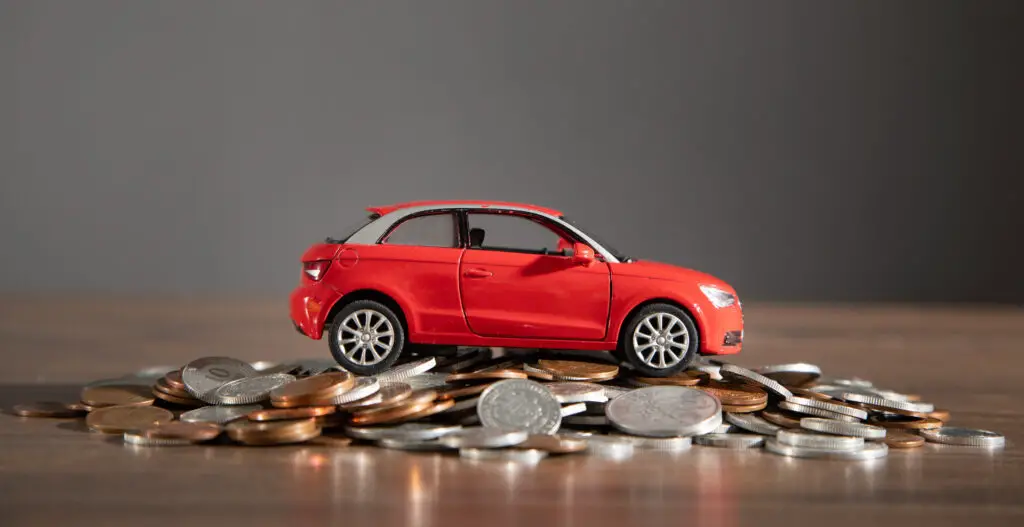 Red toy car and coins on the desk