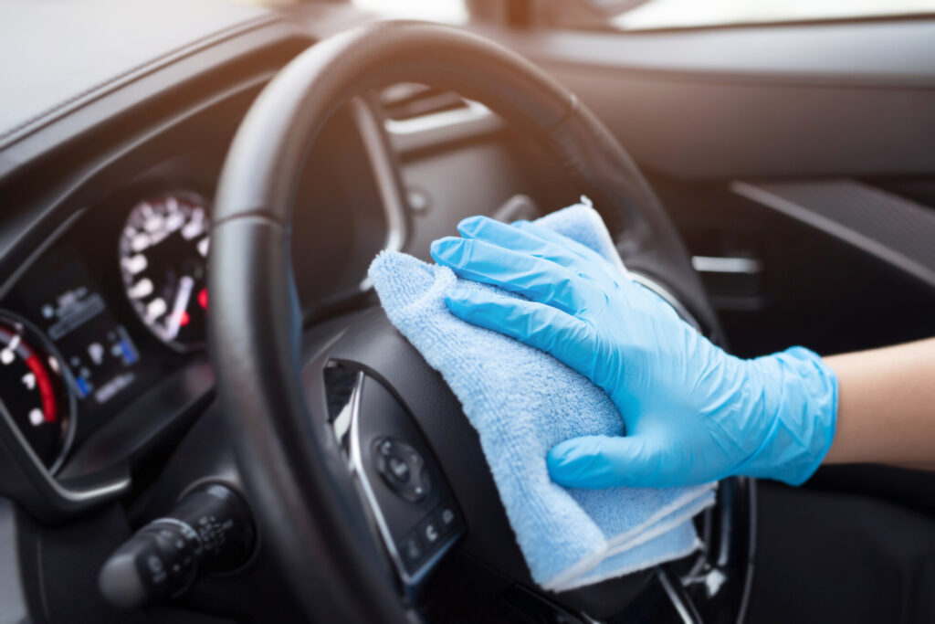 Person cleaning a steering wheel with a cloth