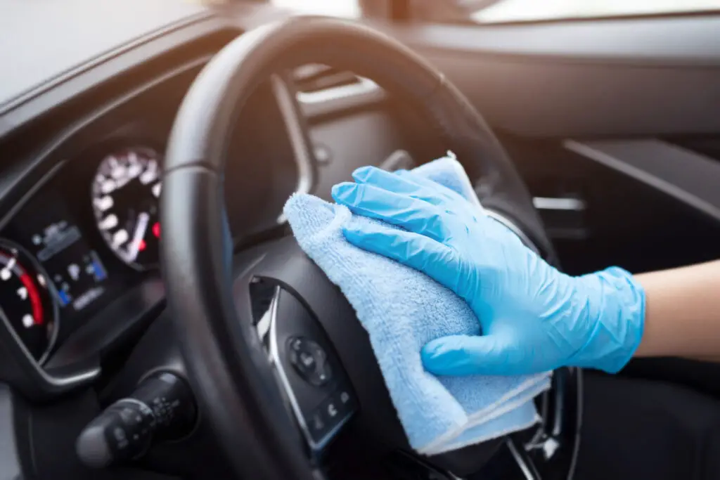 Person cleaning a steering wheel with a cloth