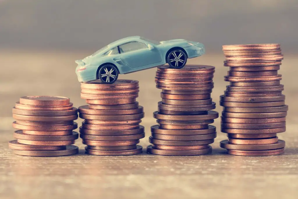 Blue car model and coins on wooden table. Saving money for a car.