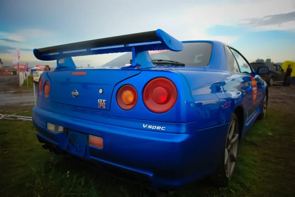 A blue Nissan Skyline R34 GT-R car from the back