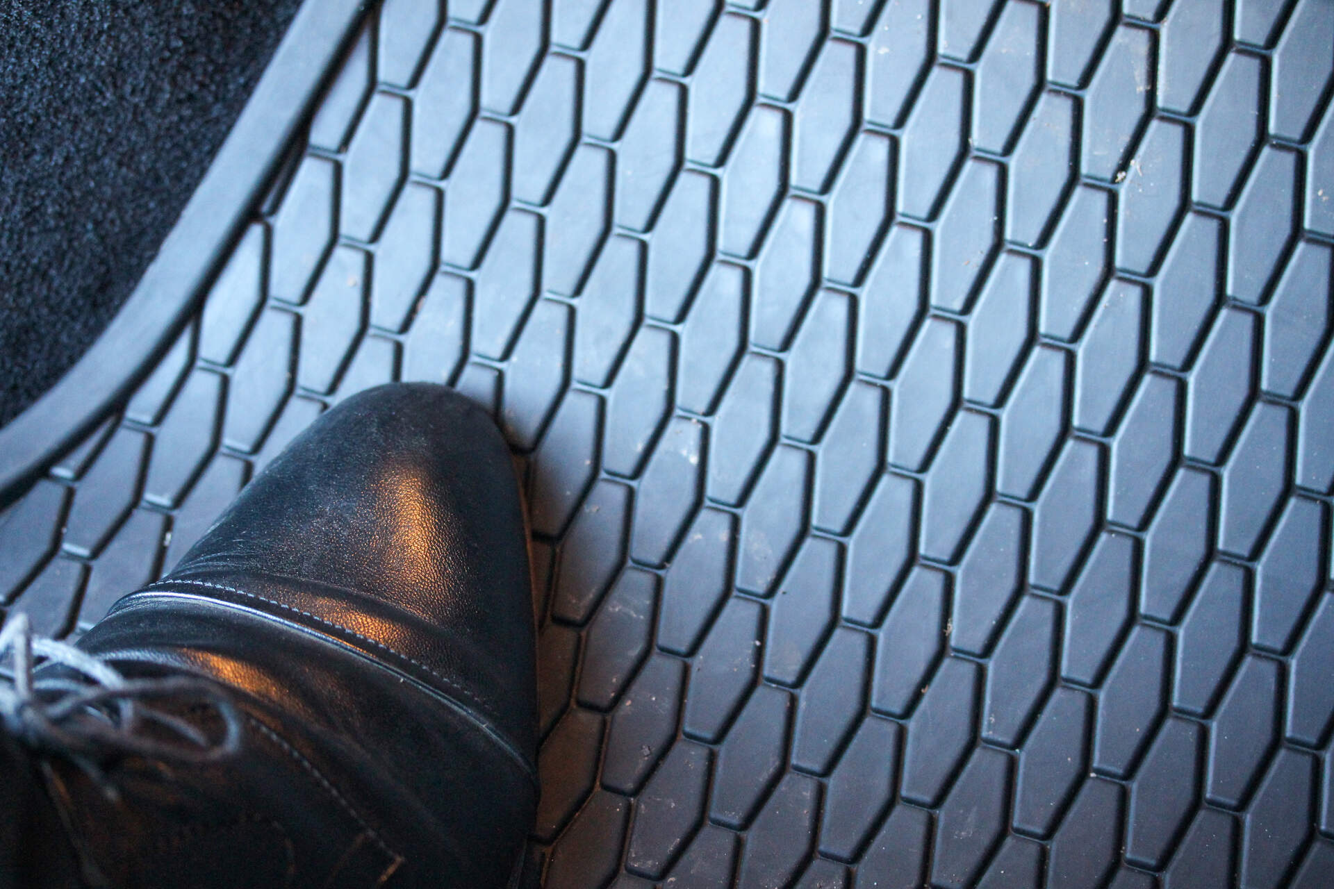 A tip of a shoe on a rubber car mat