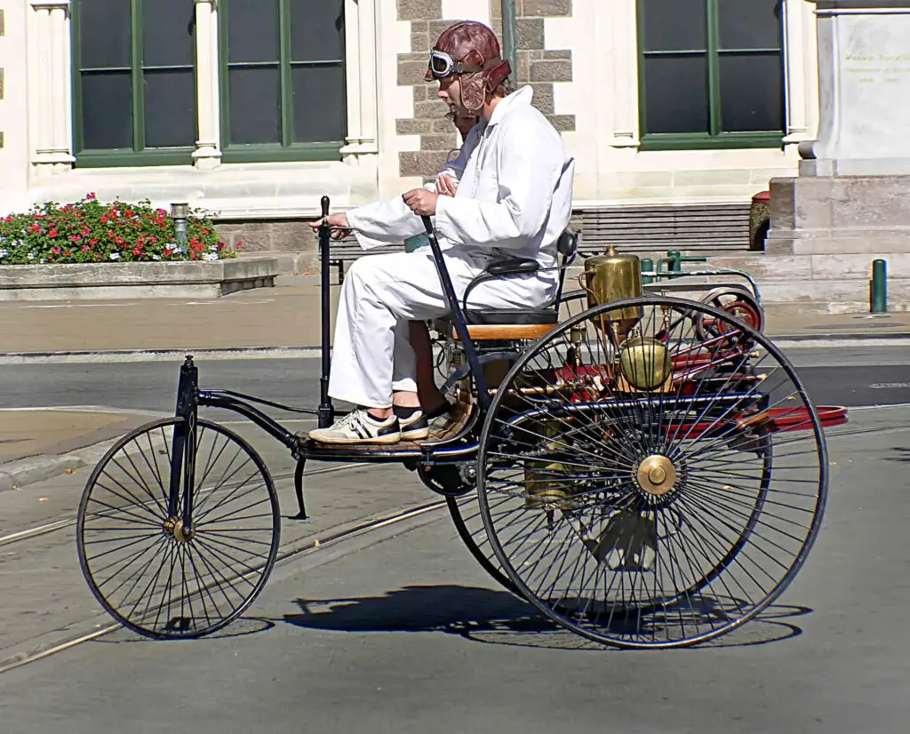 A woman in white overalls driving Motorwagen