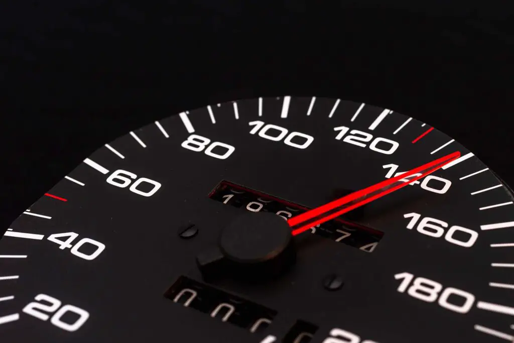 Car speedometer. Auto car speedometer shows 140 km h or miles.Closeup shot,dark black background.Automobile dangerous speed concept