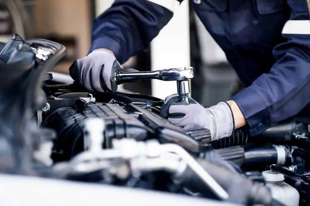 Professional mechanic working on the engine of the car in the garage. Car repair service. The concept of checking the readiness of the car before leaving.