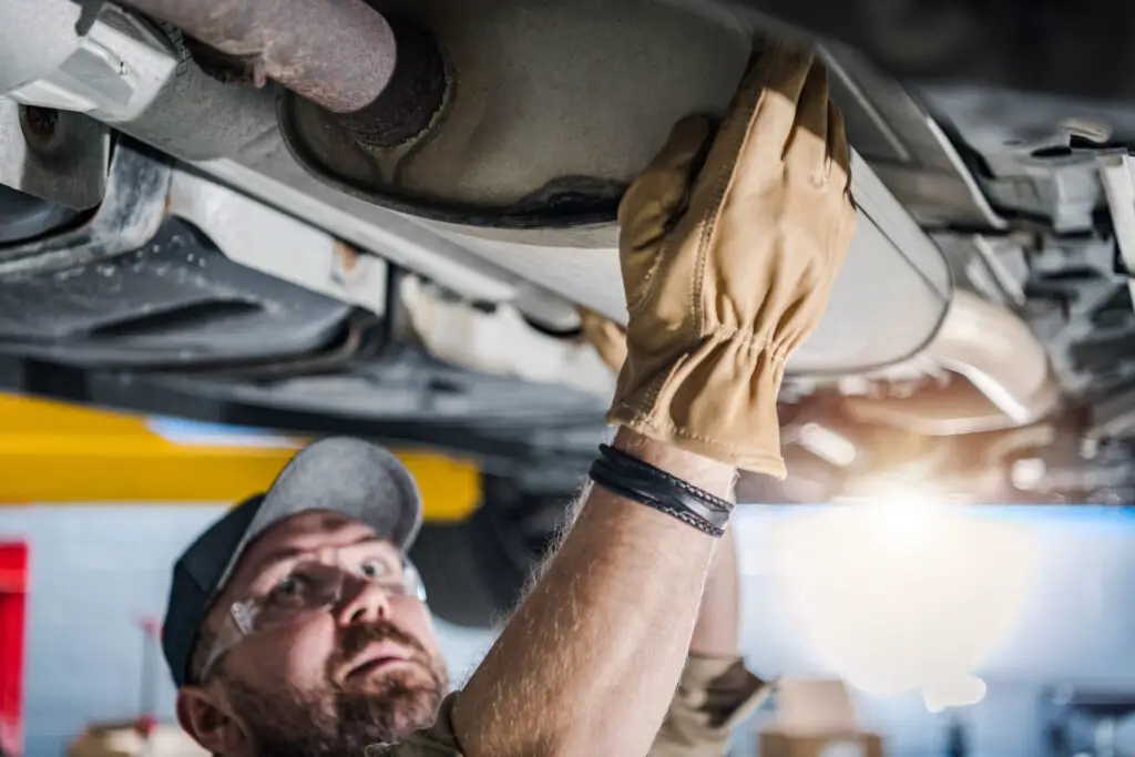 Professional car mechanic performing catalytic converter check