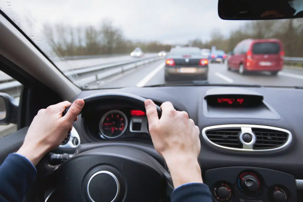 A person holding a Toyota steering wheel