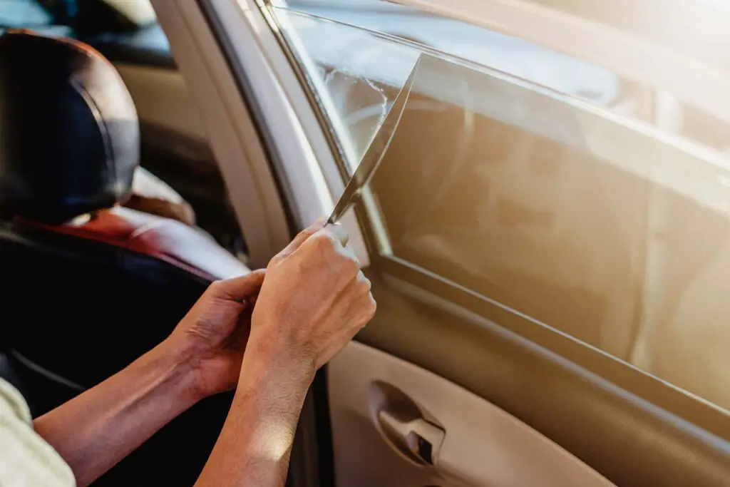 A person peeling off the tint