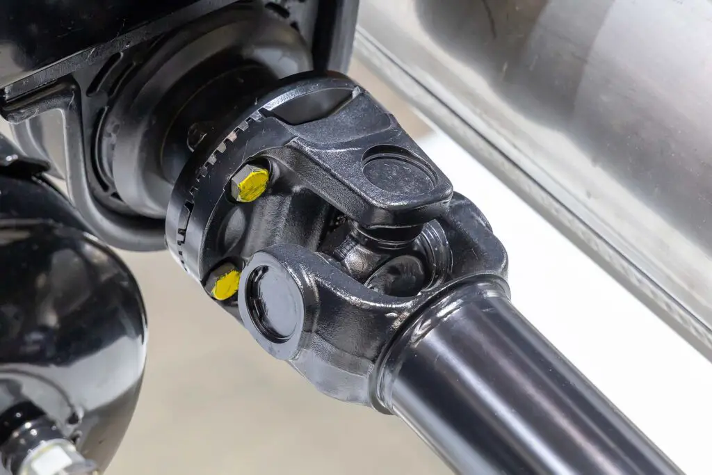 Closeup of a car cardan drive shaft with cardan cross joint and intermediate bearing support. Also known as universal joint, u-joint or cardan joint. Part of the transmission of a truck.