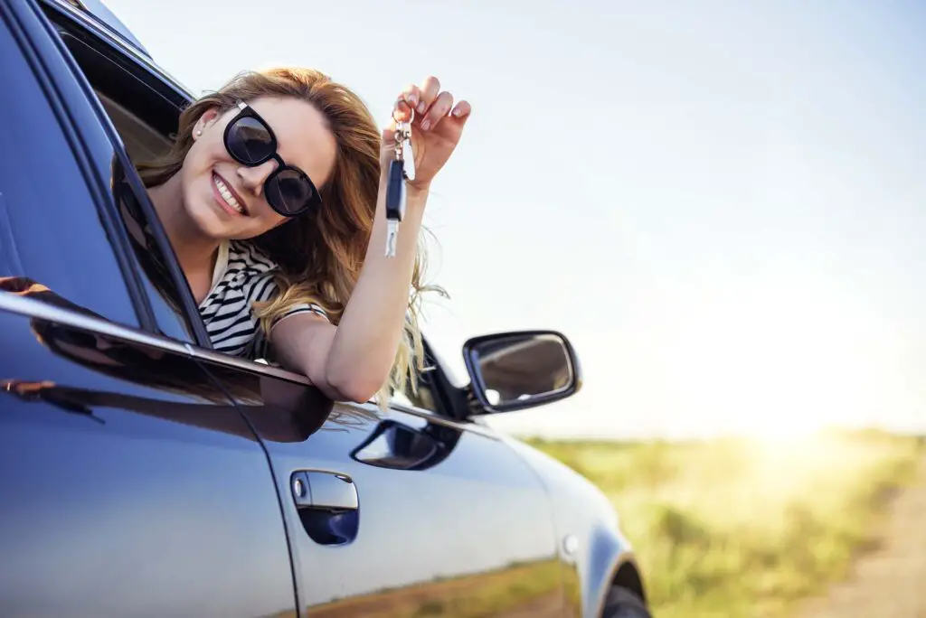 Woman holding a car key while leaning over an open car window