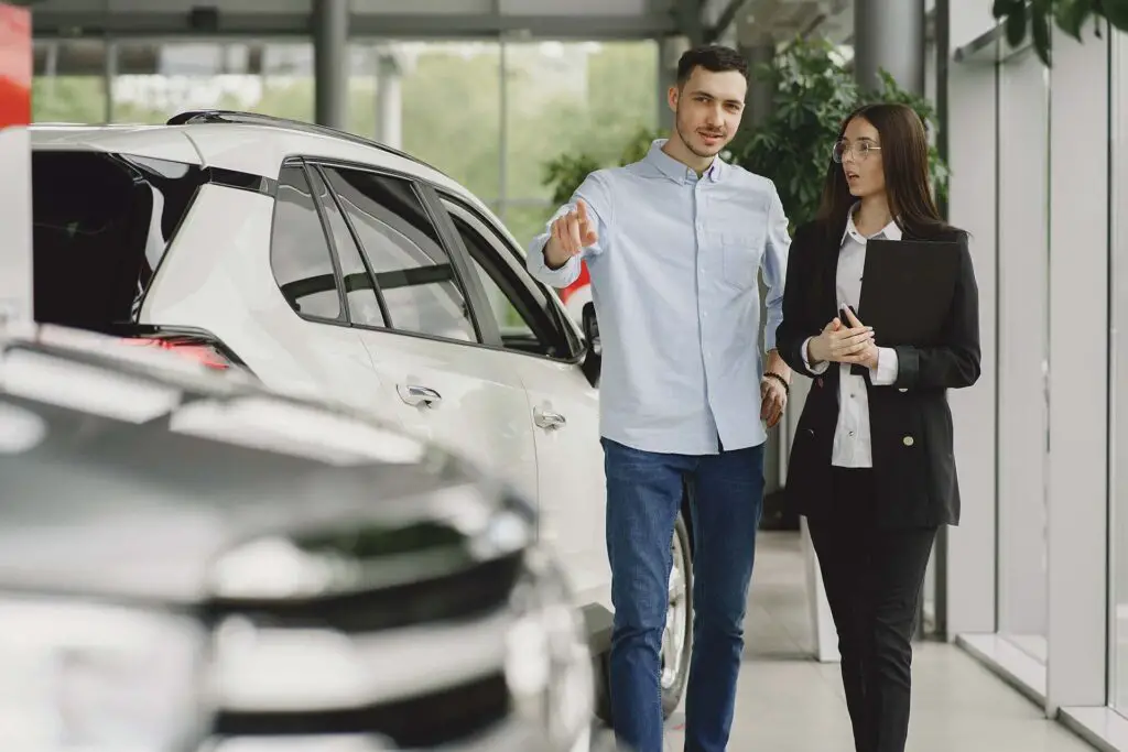 Woman in dealership shop talking to a vehicle dealer