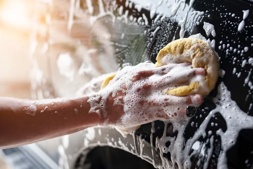A person cleaning a car with a sponge at a car wash