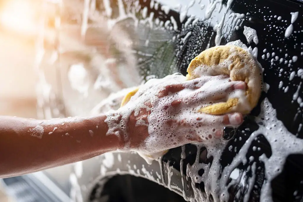 People cleaning car with sponge at car wash