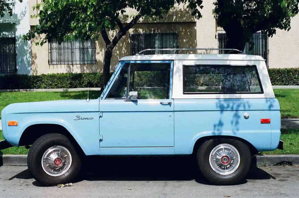A blue Ford Bronco parked in front of the house