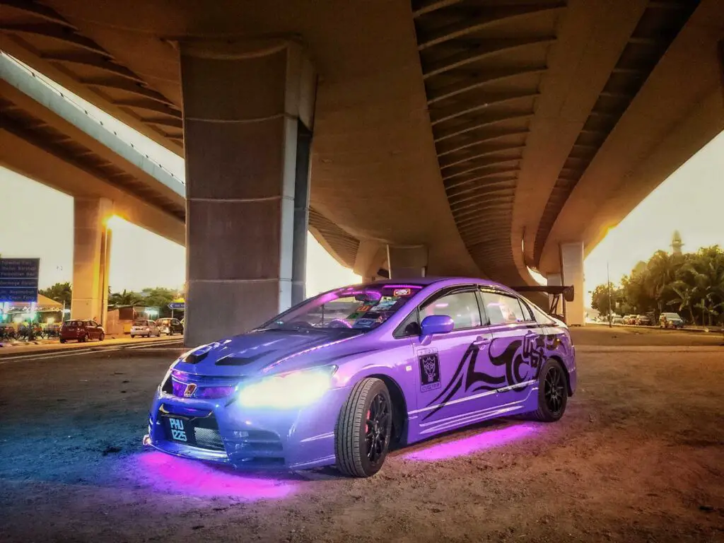 A purple car parked under a bridge