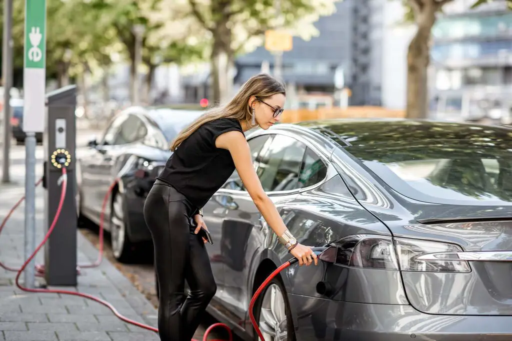 Woman charging electric car outdoors