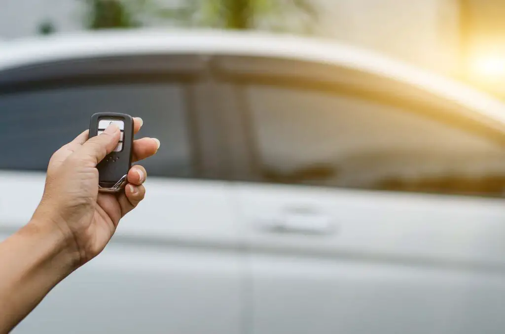 Person holding a smart key to lock the doors of a white car