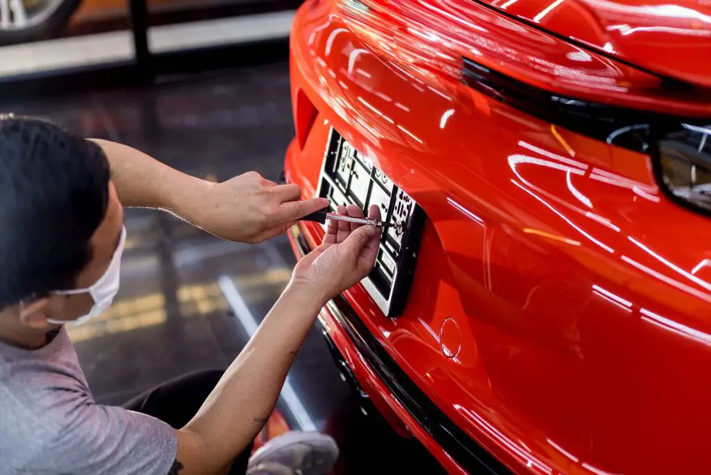 Technician changing car plate number in service center. Light background