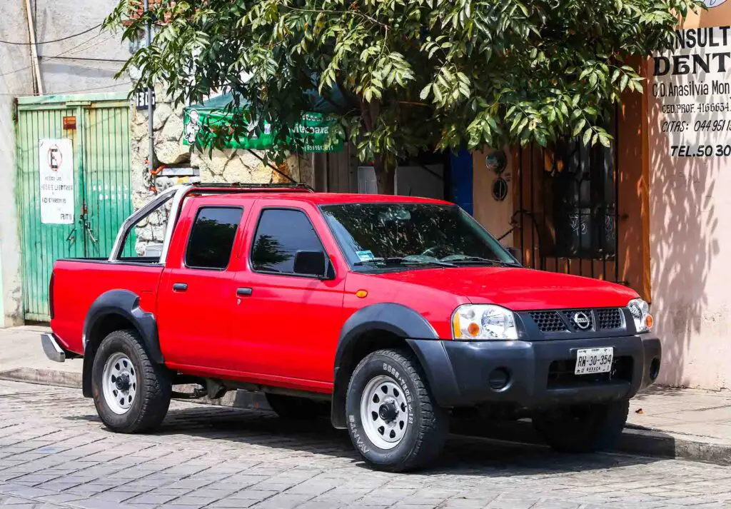 Red pickup truck Nissan Frontier in the city street.