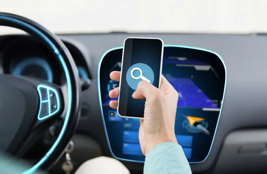 transport, business trip, technology and people concept - close up of young man hand driving car and holding smartphone with lens icon on screen