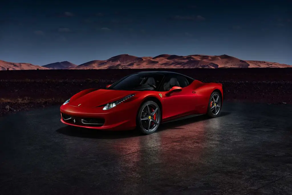 A red Ferrari 458 Italia standing in front of the desert dunes. Engine V8, 4.5L, 570HP. Electronic assembly with Moroccan landscape. Katowice, Poland, 23/12/2013