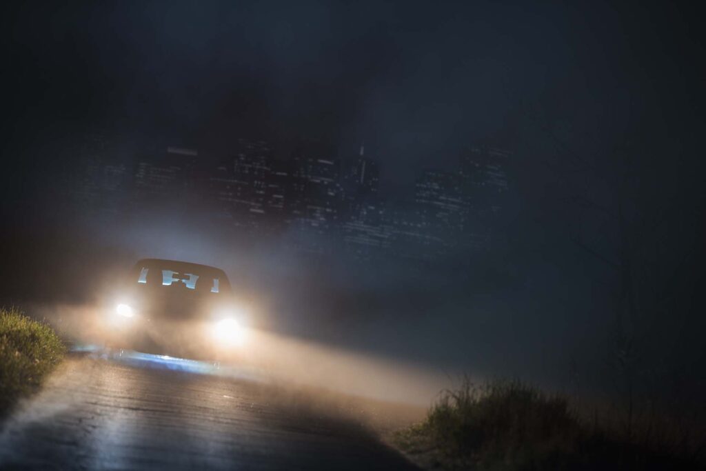 Car with headlights on driving through the night