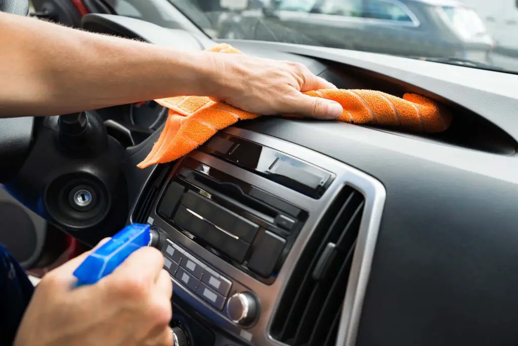 Cropped image of mature male worker cleaning car dashboard