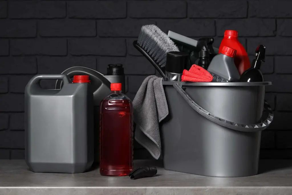 Different car cleaning products on grey table near black brick wall