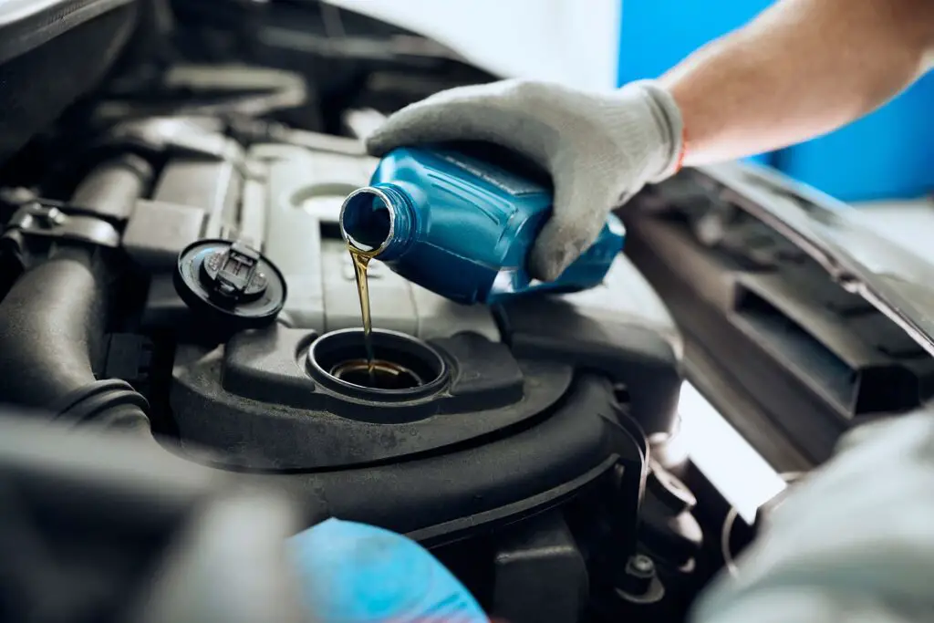 A close-up of the mechanic pouring motor oil