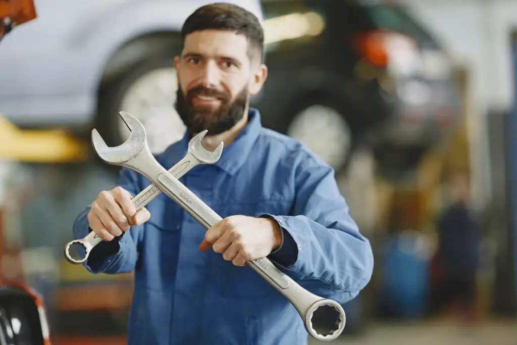 A man using a wrench to fix his parking brake cable