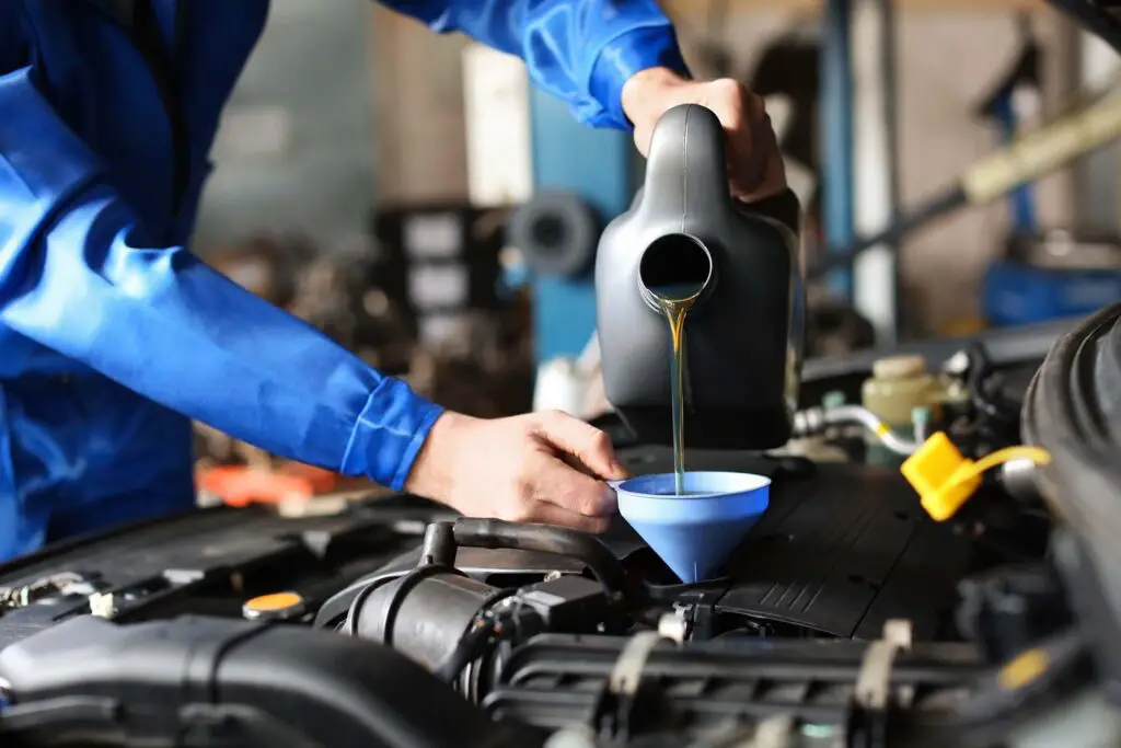 Mechanic pours fresh oil into a car