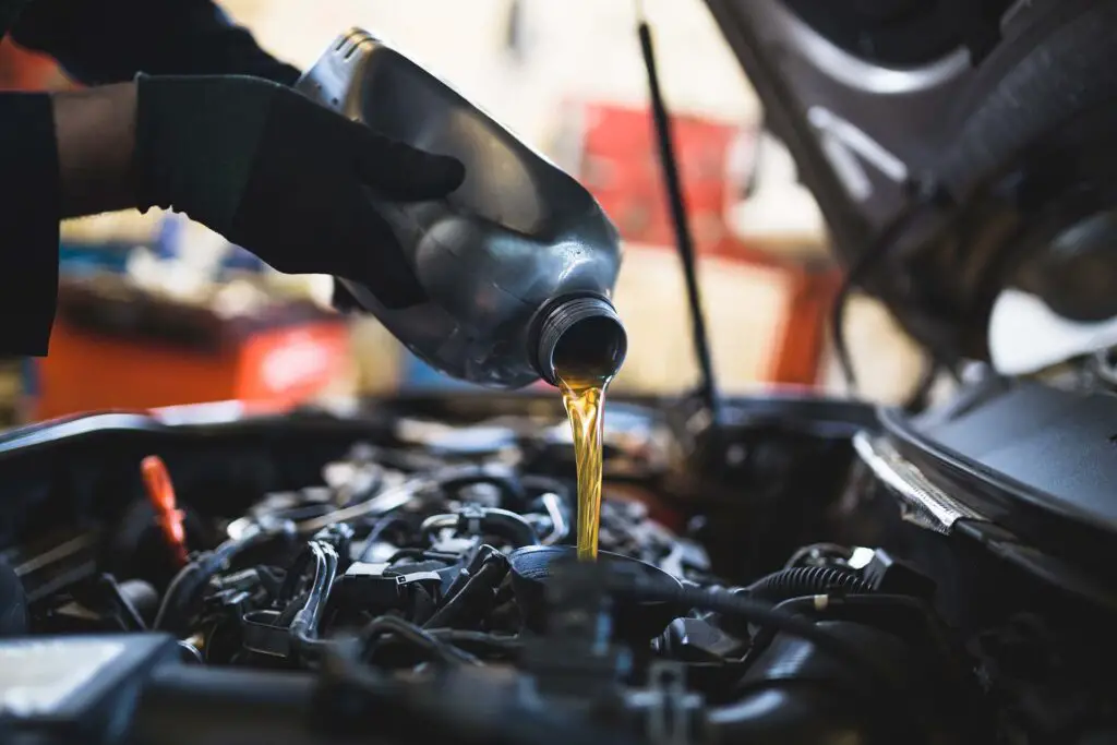 A car mechanic replacing and pouring fresh oil into the engine