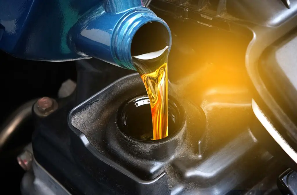 A person pours oil into an engine