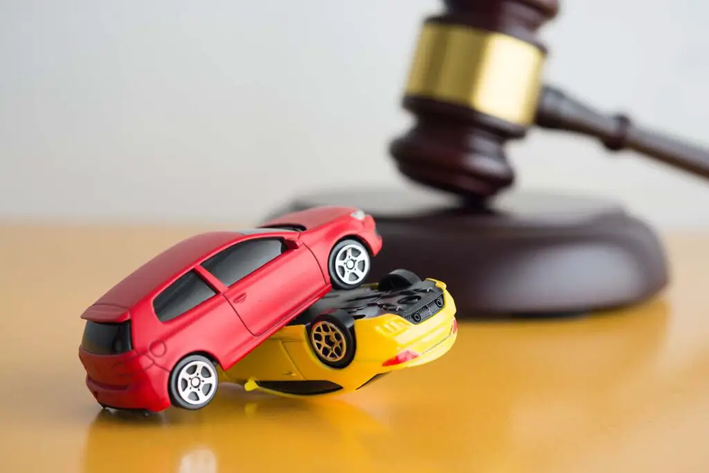 Red and yellow car model crash, wooden judge hammer on wooden table
