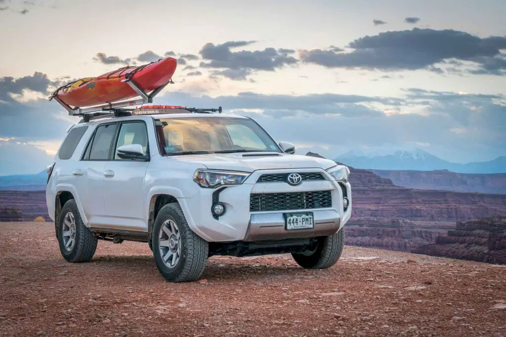 Toyota 4runner SUV (2016 trail edition) with a whitewater kayak on roof racks in the Colorado RIver canyoin near Moab.